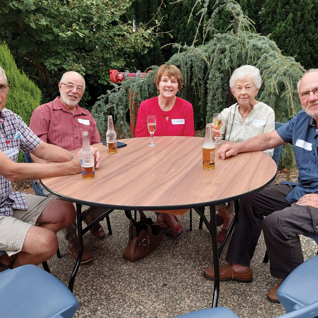 Volunteers sitting around a table enjoying beverages outside at the Empire Theatres precinct