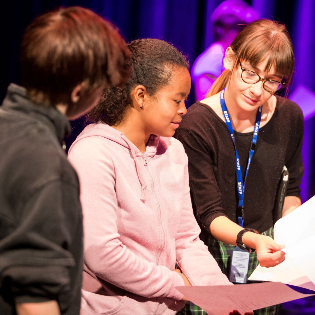 Two young people being handed script by staff.