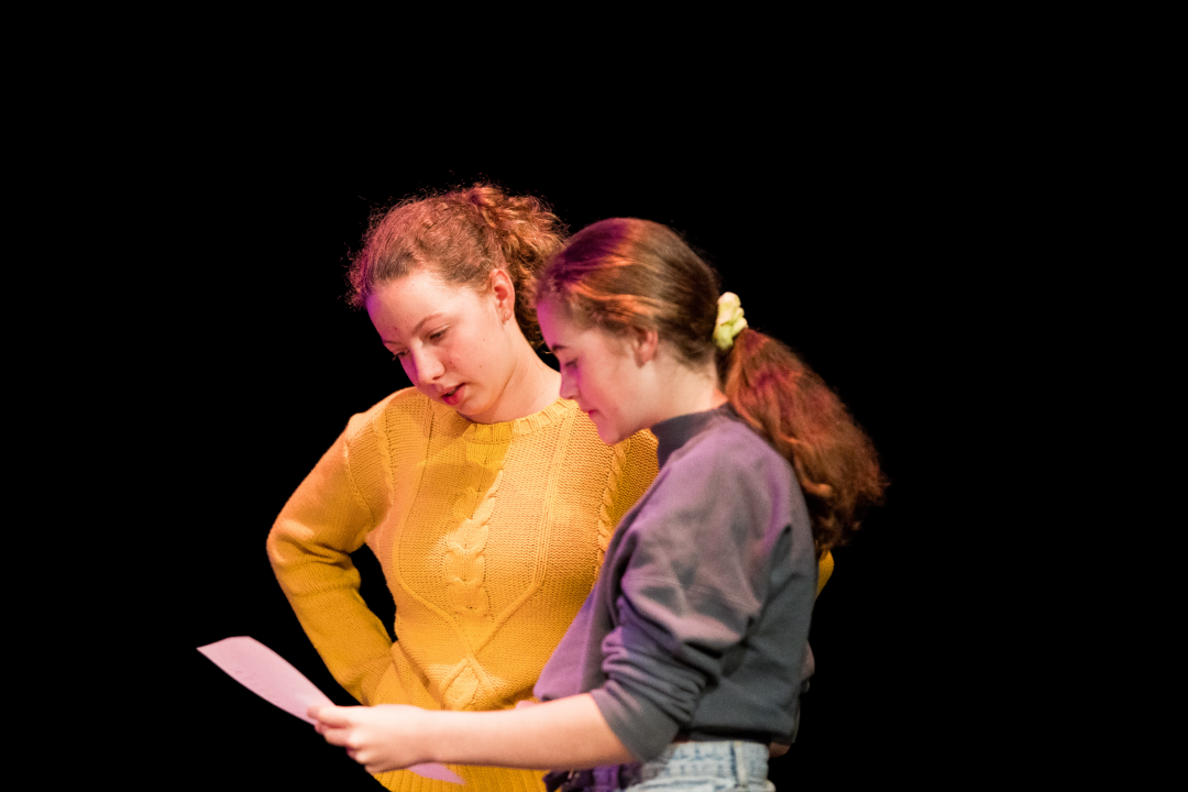 Two youth arts performers reviewing a script together. 