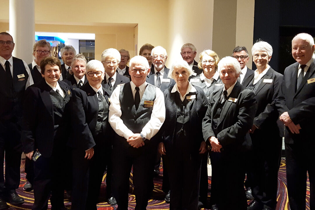 Empire volunteers in black and white dress posing for a group photograph in the theatre