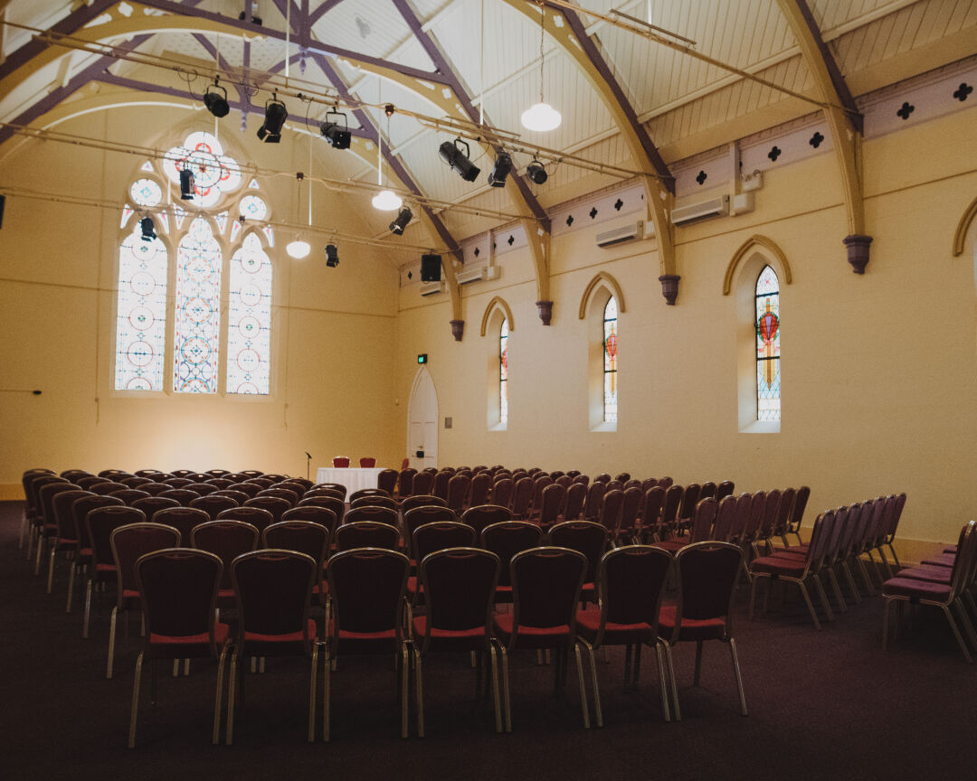 Church theatre set up with large and colourful Stained glass window at the back of the room