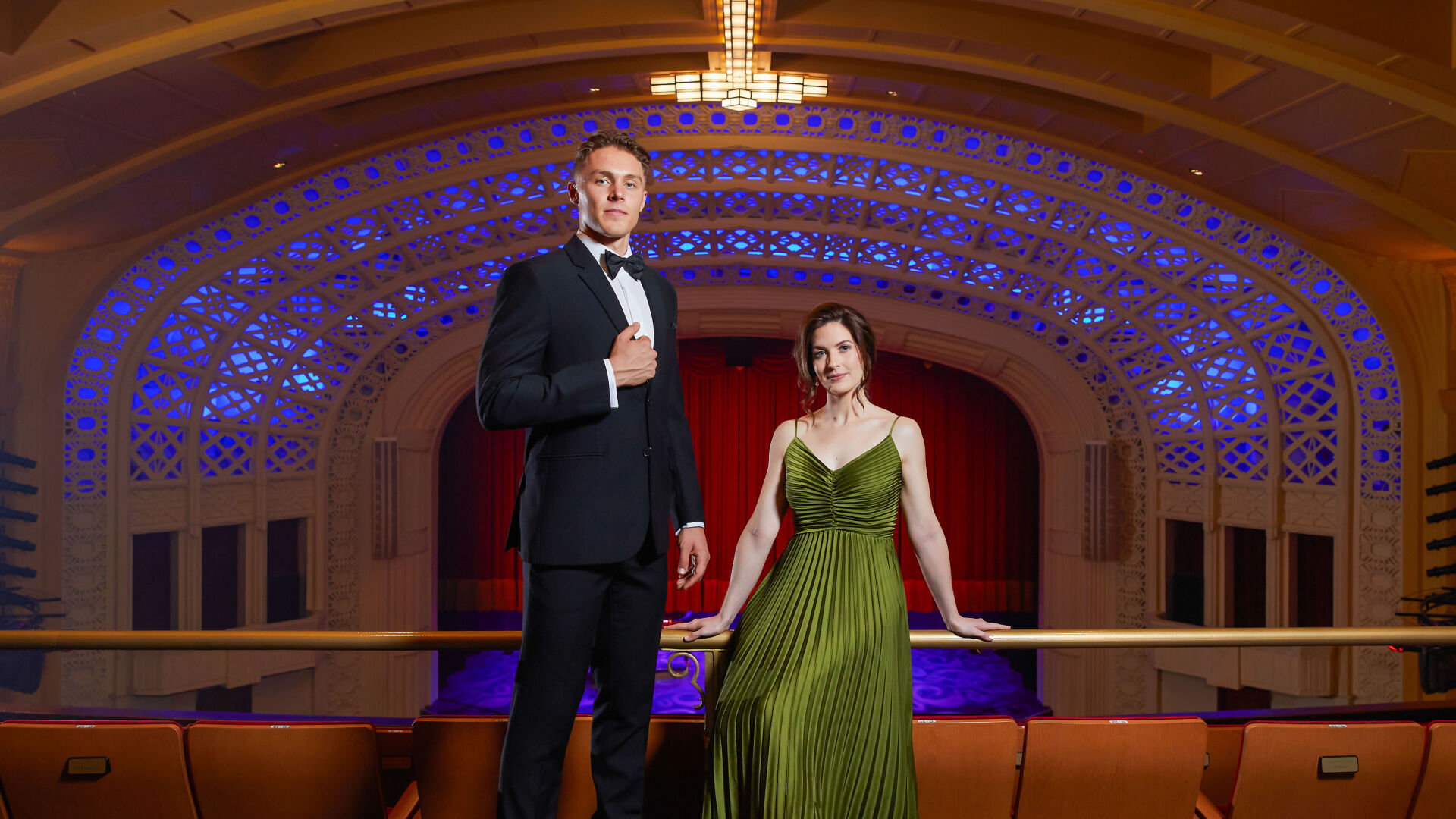 Gabriel Tiller standing on the Empire balcony in front of the lighted proscenium arch with Shannon Gralow 